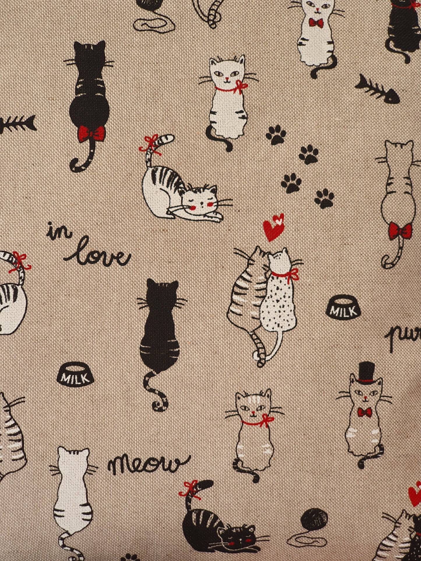 Close of up of the 'in love' cat pattern fabric. The black and white cats, paws and hearts pattern is on a neutral background linen look fabric.