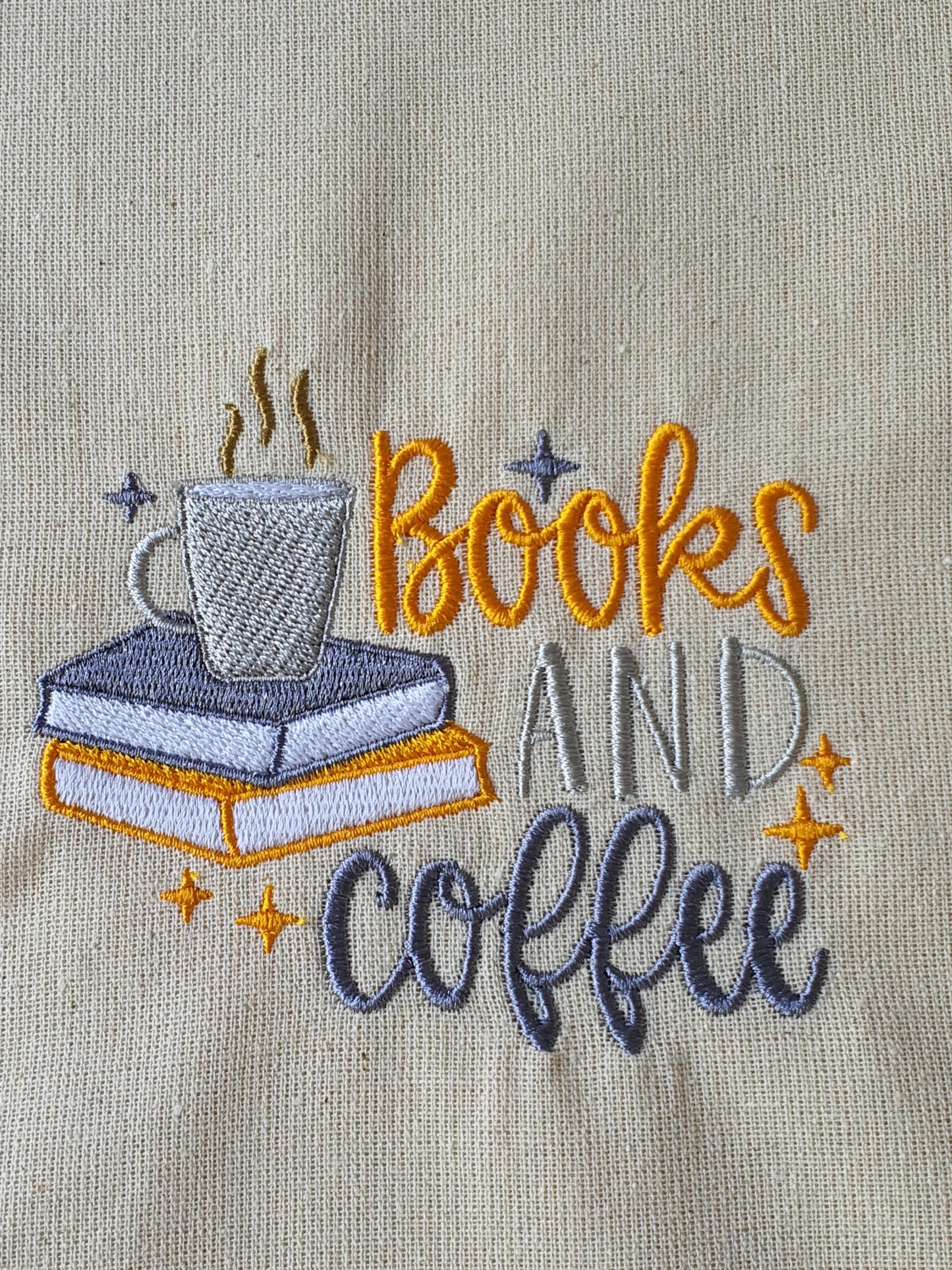 Close up of the orange and grey machine embroidered Books and Coffee pattern on the Tote Bag.