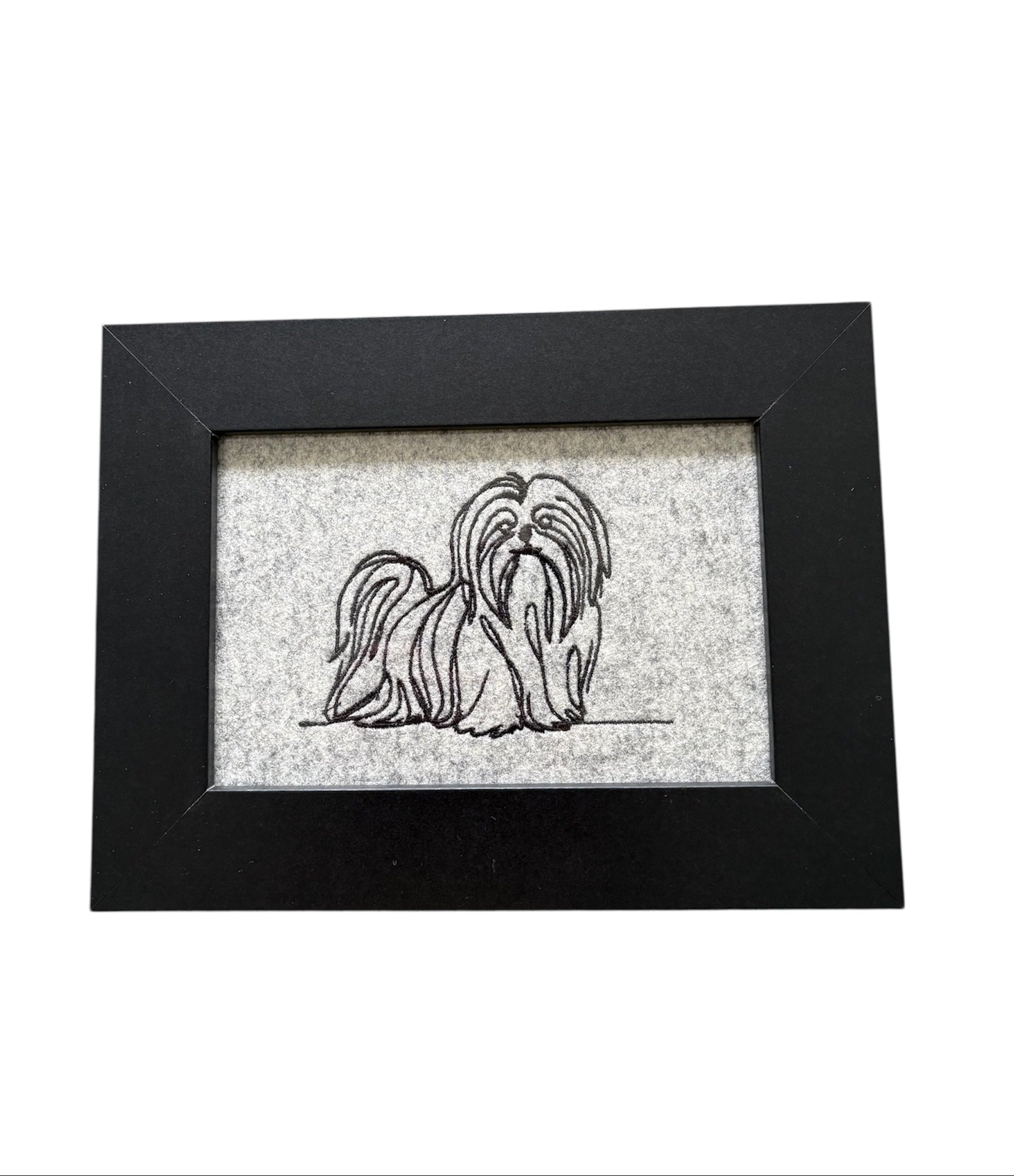 Framed machine embroidered sketch style pattered Shih Tzu.  The sketch style pattern of the dog is in black on light grey boiled wool and mounted in a black wooden frame.  The glass fronted display area is 4 inches by 6 inches (10cms x 15cms) and the total size of the frame is 6 inches by 8 inches (15cms x 20cms)  The frame can be wall hung or displayed easel style.