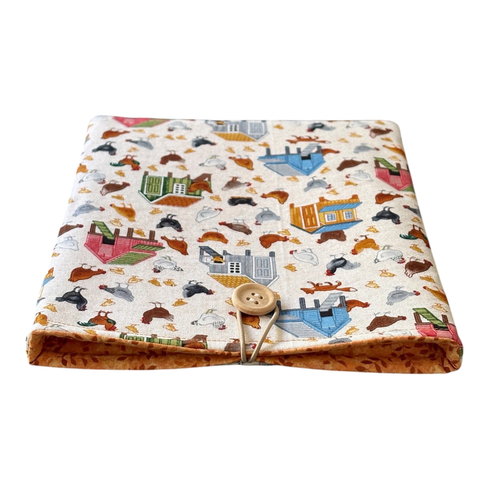 The handmade Book Pouch is padded with fusible fleece, lined with orange leaf patterned fabric and fastens with elastic and a button.
