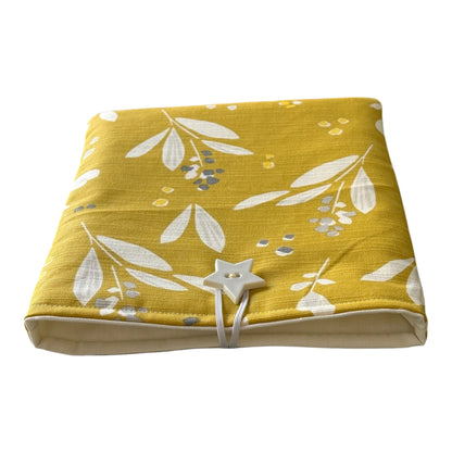 The outer fabric of the handmade Book Pouch is a botanical pattern with white leaves and grey and white berry type shapes on a mustard yellow background.