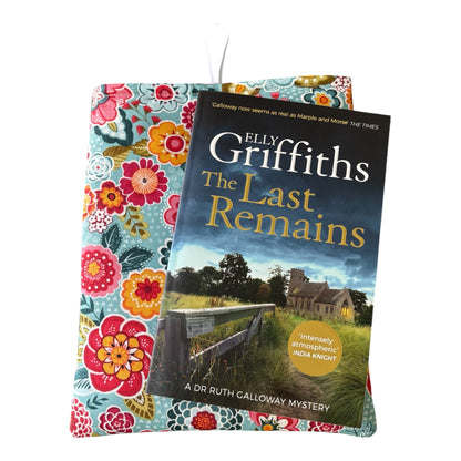 The handmade Book Pouch has been made with colourful floral cotton fabric, which includes colours of teal, red, orange, yellow and green.  The Book Pouch is padded with polyester wadding, lined with neutral cotton fabric and has button and elastic fastening.  Please note the book in the photo is not included and is for illustrative purposes only.