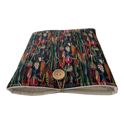 The handmade padded pouch has elastic and button fastening to keep a book or device safe whilst being carried on the go in a bag.  The pouch has been made with ebony botanical plants cotton fabric, is padded with polyester wadding and is lined with complementing neutral fabric.