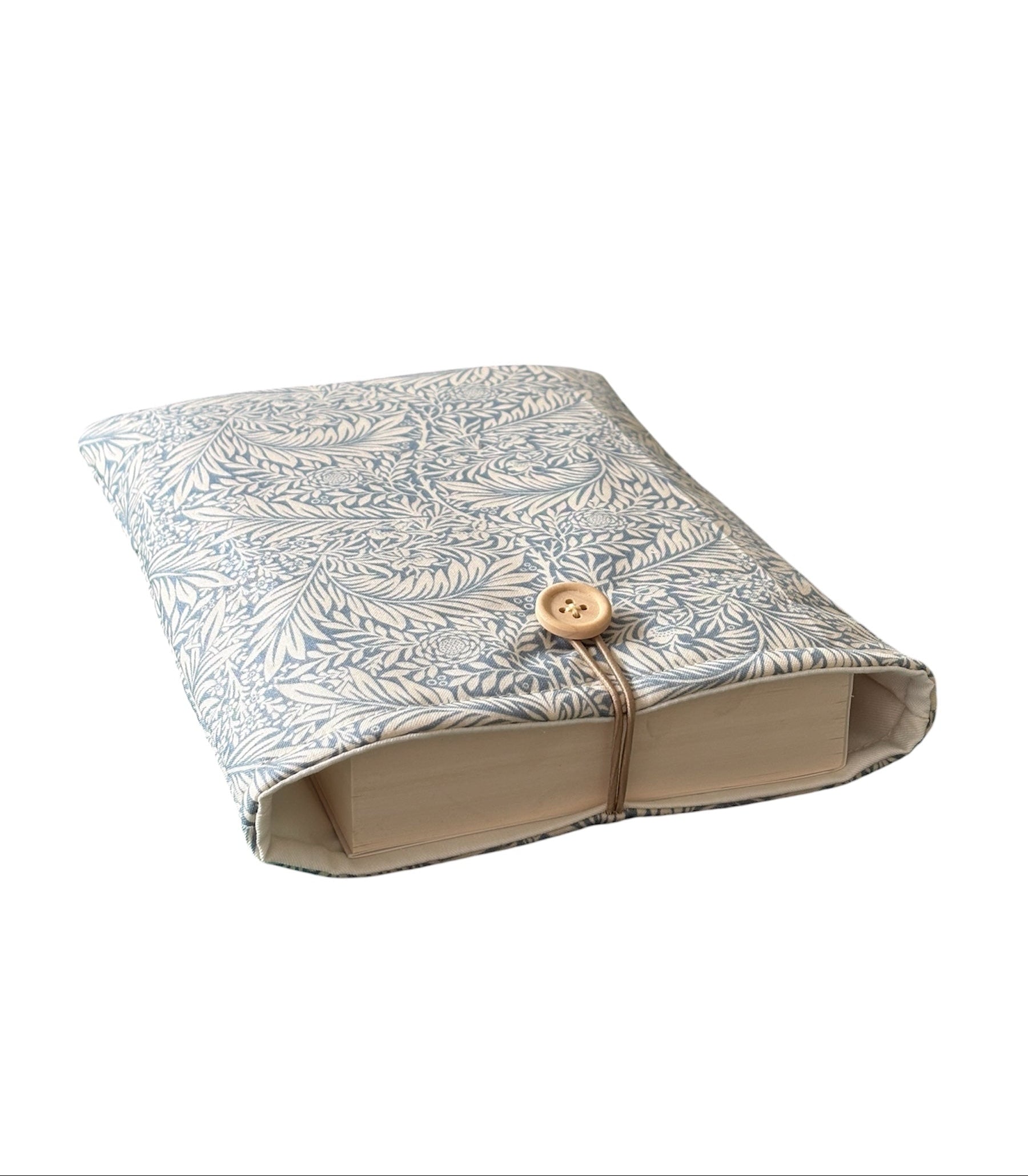 The handmade Book Cover has been made using William Morris Larkspur design fabric in blue and cream, is padded with fusible fleece, lined with neutral fabric and fastens with elastic and button.  Please note the book is not included and is for illustrative purposes only.