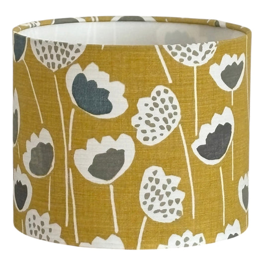 The handmade drum lampshade is 25cms in diameter and 21cms in height. The Skandi style floral white and grey pattern is on a saffron yellow background. 