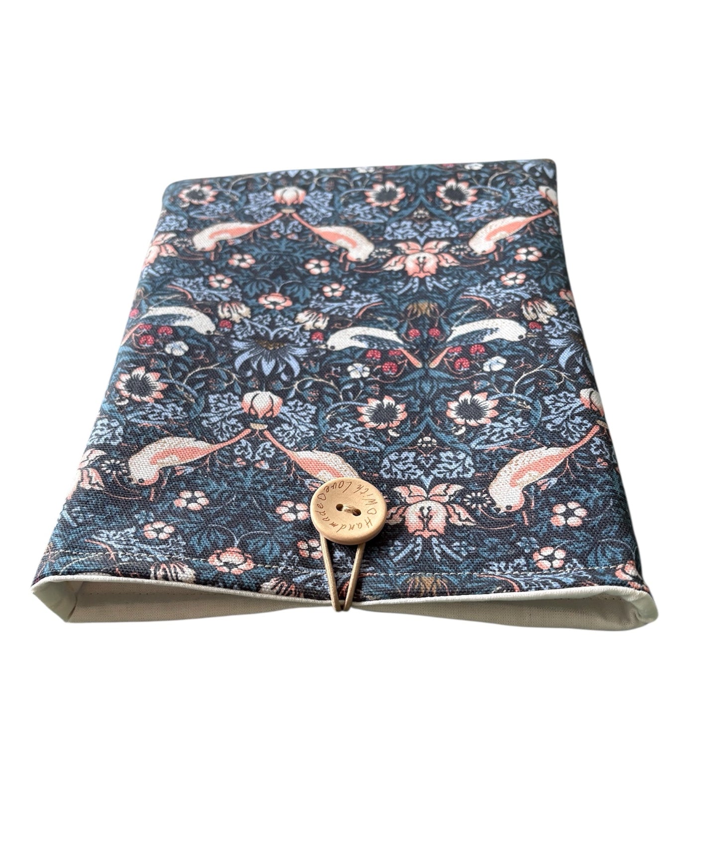 The handmade Book Pouch has elastic and button fastening as shown in the photo.  The neutral lining can also be seen in the photo.